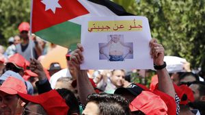أحد المحتجين في عمان يرفع لافتة تطالب الحكومة بالابتعاد عن جيوب المواطنين- جيتي