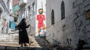 سيدة تسير بجانب جدارية لمحمد صلاح في أحد أحياء القاهرة- جيتي