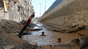 أطفال يسبحون في بركة مياه خلفتها غارة جوية - حي الشعار  حلب سورية 14-7-2014