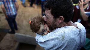 غزي يقبل طفلته التي قتلت جراء القصف الإسرائيلي قبل دفنها - فيس بوك