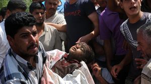 شاب يحمل جثة لأحد الأطفال الذي قتل بقصف إسرائيلي - الأناضول