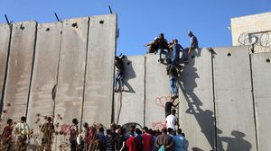 فلسطينون يتسلقون الجدار العازل للصلاة في المسجد الأقص- الأناضول