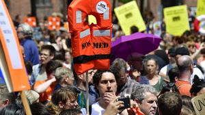 أحد المتظاهرين بألمانيا يحمل سترة نجاة أثناء مظاهرة للتنديد بإغلاق موانئ البحر المتوسط- جيتي