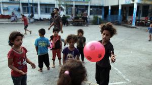 أطفال غزيون يلعبون بإحدى ساحات مدارس وكالة الغوث - الأناضول 