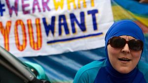 سيدة تشارك بالبوركيني في احتجاج وخلفها لافتة كتب عليها "ارتد ما تشاء"- تويتر