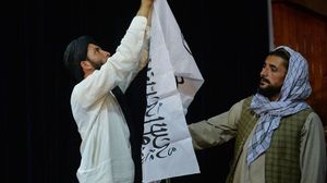 مقاتلان من طالبان يرفعان علم الحركة في مؤتمر صحفي- جيتي