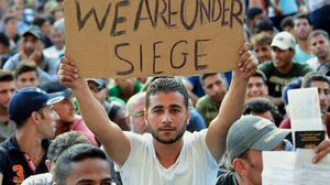 مهاجر يرفع لافتة كتب عليها "نحن محاصرون" - أ ف ب