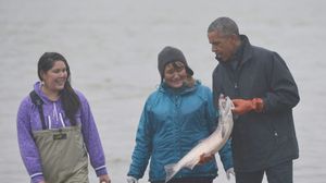 الرئيس أوباما يحمل سمكة سلمون أثناء لقائه صيادين وأسرهم في ألاسكا - أ ف ب