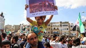 طفل من مهجري تدمر يرفع لافتة ضد الأسد- جيتي