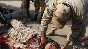 ضابط في الجيش الإيراني يتفحص جثة أحد قتلى الهجوم- مهي الإيرانية