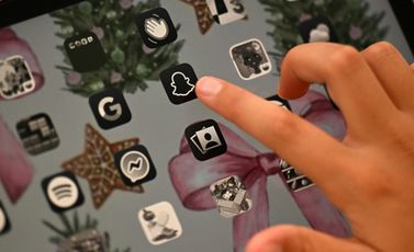 طفلة تبلغ 10 سنوات تشير إلى شعار تطبيق سنابتشات على هاتف محمول في منزلها في غرب سيدني بتاريخ 10 كانون الاول/ديسمبر 2025