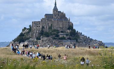 سياح يتوجهون مشياً إلى موقع مون سان ميشال السياحي في شمال غرب فرنسا في 25 تموز/يوليو 2023