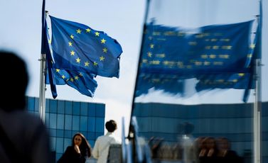 مارة يسيرون أمام علم الاتحاد الأوروبي في منطقة مقر الاتحاد في بروكسل في 23 أيلول/سبتمبر 2021
