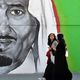 سعوديتان تسيران بجانب جدارية للملك سلمان في الرياض - جيتي