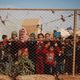 أطفال سوريون نازحون خلف سور في مخيم بالقرب من قرية كفر لوزين في ريف إدلب الشمالي - أ ف ب