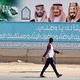 سعودي يسير بجانب لافتة لرؤية 2030 في الرياض- جيتي