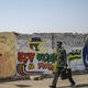 عسكري سوداني يسير بالقرب من جداريات رسمها المحتجون- جيتي