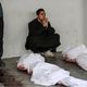 فلسطيني يجلس أمام جثامين اثنين من أقاربه الشهداء في دير البلح- الأناضول