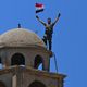 جندي سوري يرفع علم بلاده في القنيطرة فوق كنيسة القديس جورج الأرثوذكسية - جيتي