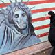 إيرانية تمر أمام جدارية تهاجم أمريكا - (أرشيفية) أ ف ب