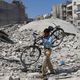 سوري يحمل دراجة وسط الأنقاض في حلب- أ ف ب