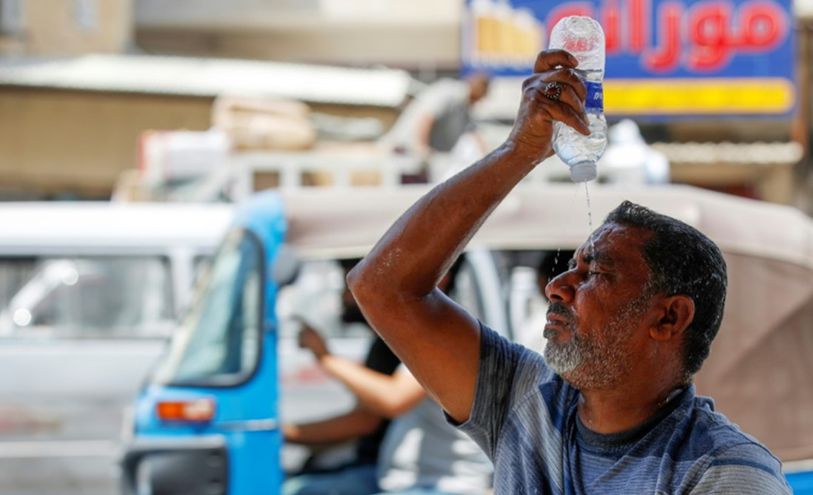 رجل يضع الماء على وجهه في بغداد ليقاوم درجات الحرارة المرتفعة في 13 آب/أغسطس 2023